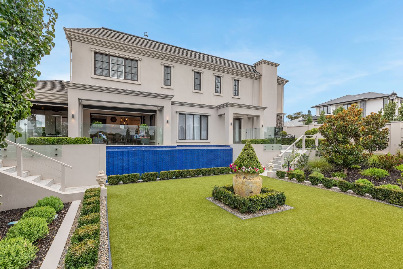Rendered two-storey home with a pool and formal garden