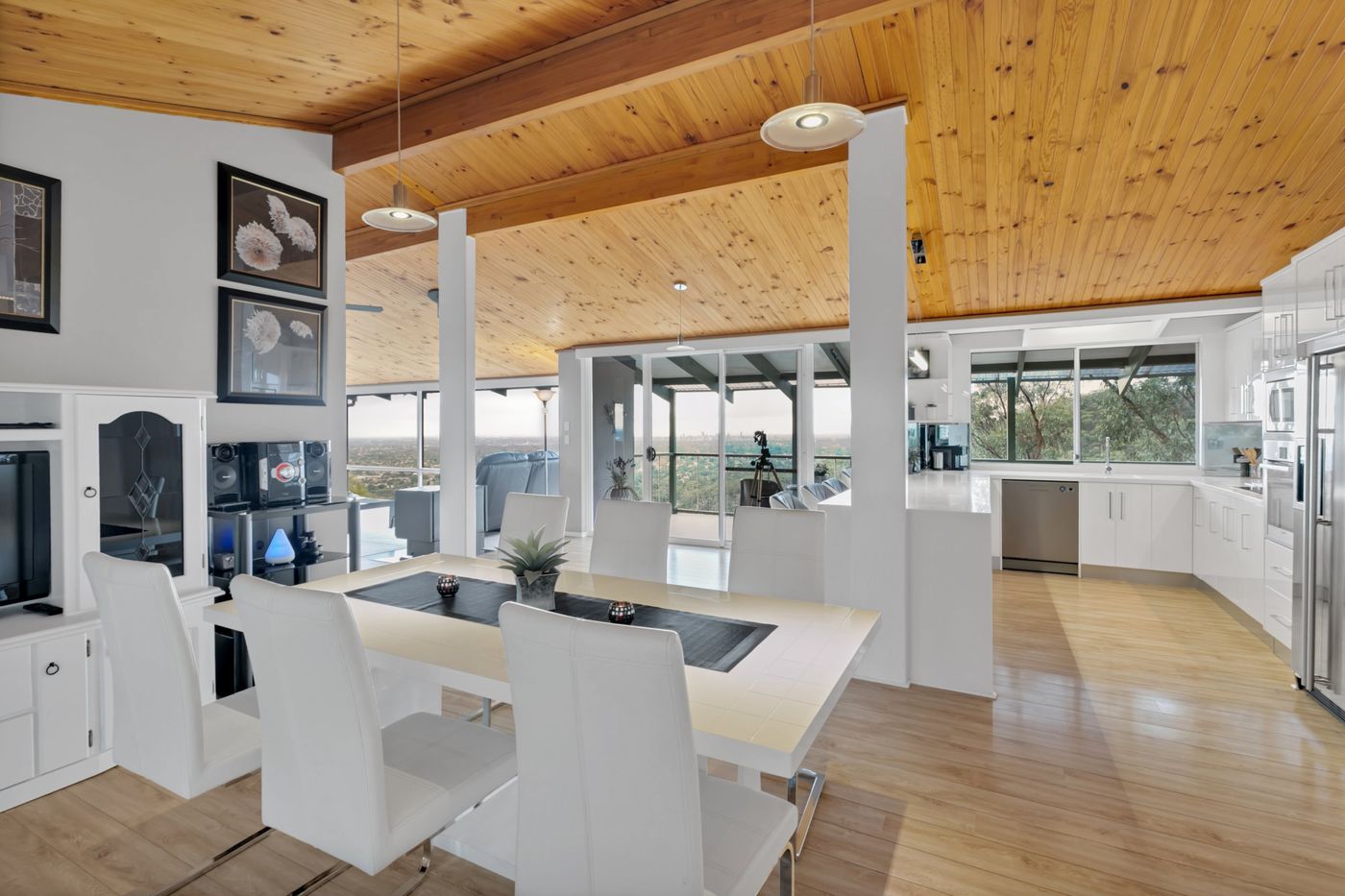 Dining and kitchen under a timber-lined ceiling with city views